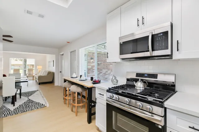 a kitchen with stainless steel appliances a stove a sink cabinets and a wooden floor