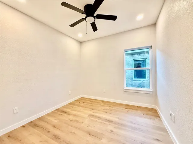 an empty room with a window and a ceiling fan