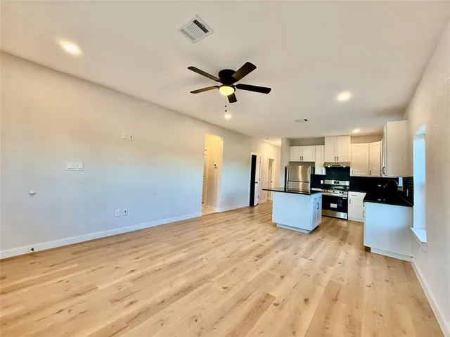 a kitchen with stainless steel appliances kitchen island a sink dishwasher a stove and a refrigerator with wooden floor