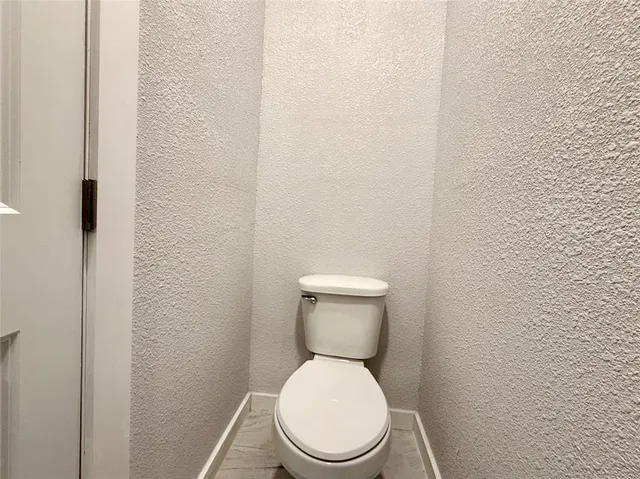 a white toilet sitting next to a white wall
