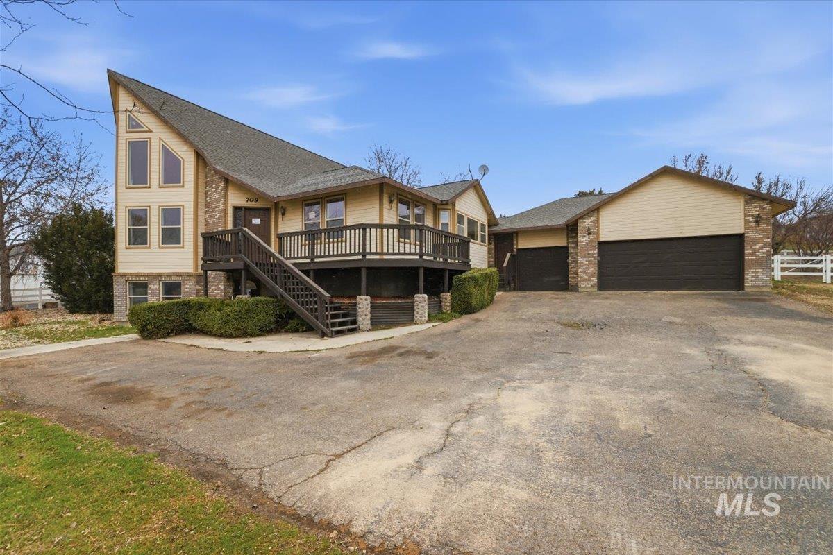 View of front of property featuring a deck, asphalt driveway, and brick siding