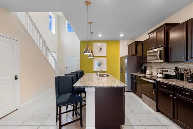 a kitchen with stainless steel appliances granite countertop a sink a stove a refrigerator cabinets and chairs