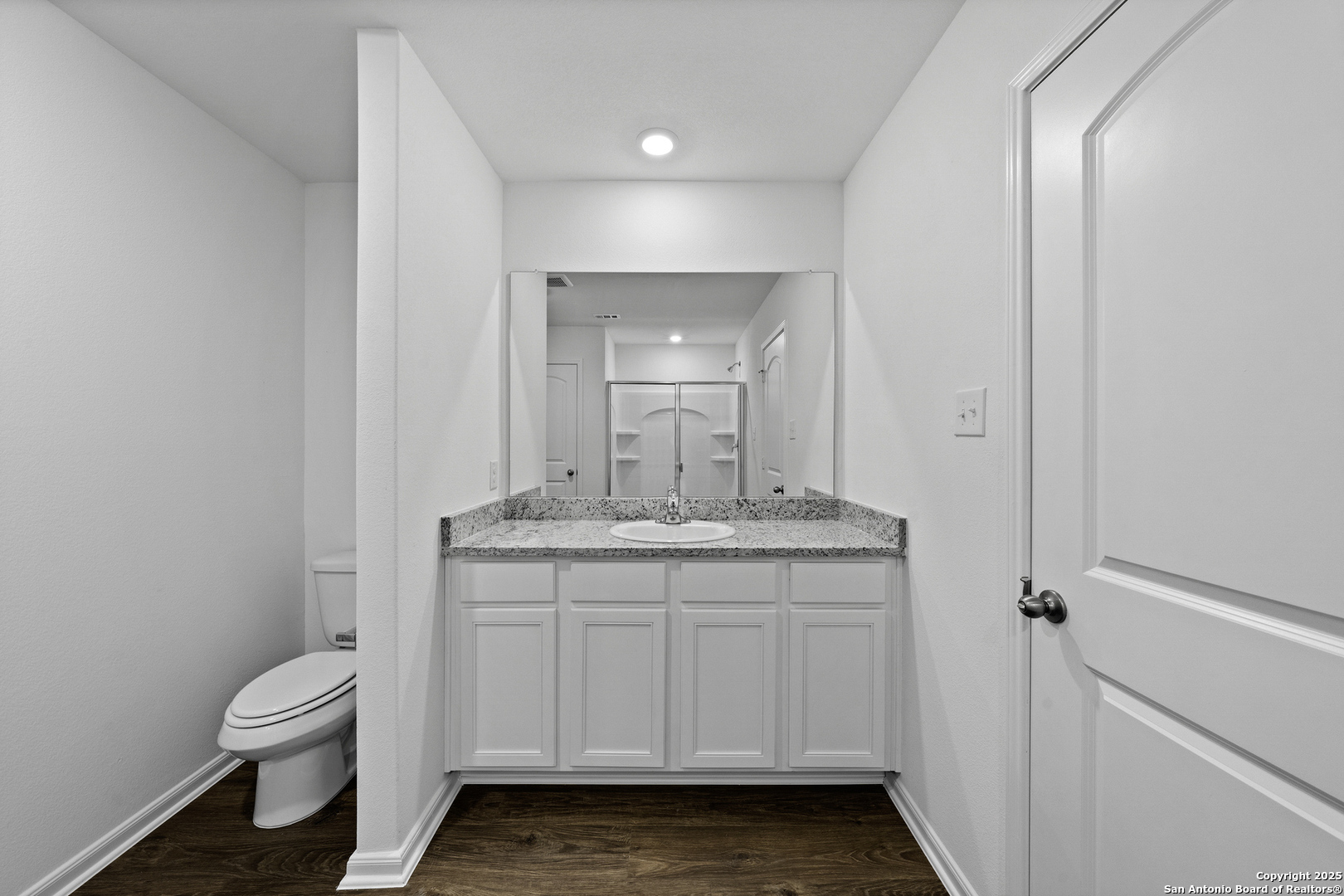 16004 Stratford Cove Lytle, TX 78052 - Photo 13 of 29 a bathroom with a granite countertop toilet a sink and a mirror