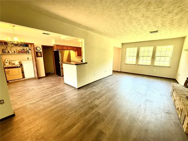 a view of a room with kitchen appliances and wooden floor