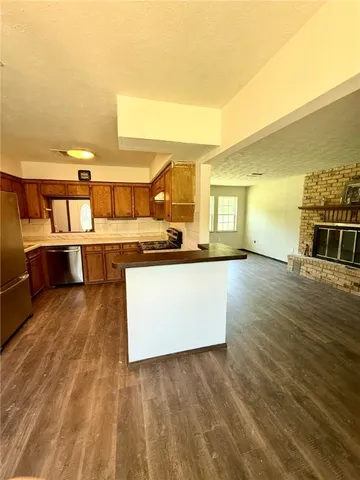 a view of a kitchen with kitchen island a sink wooden floor and a large window