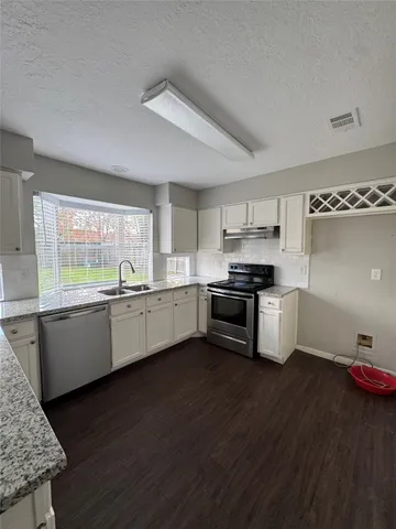 a kitchen with granite countertop a sink cabinets and stainless steel appliances