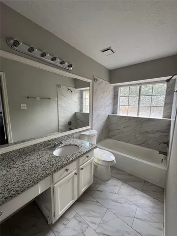 a bathroom with a granite countertop sink toilet and bathtub