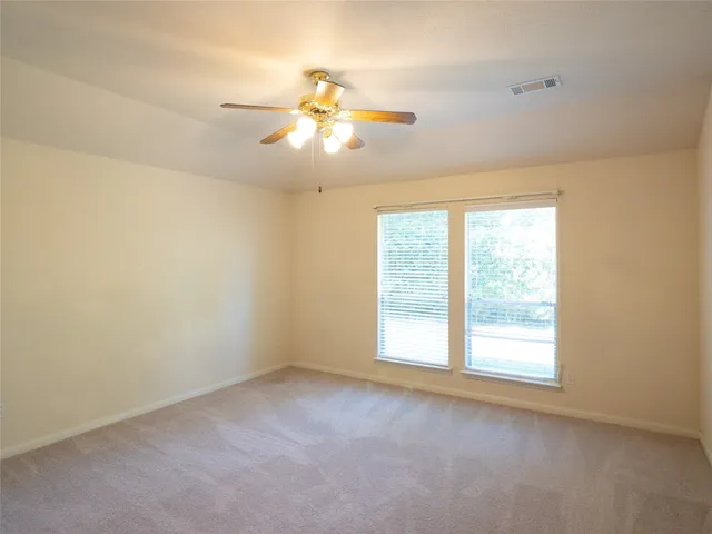 an empty room with window and ceiling fan