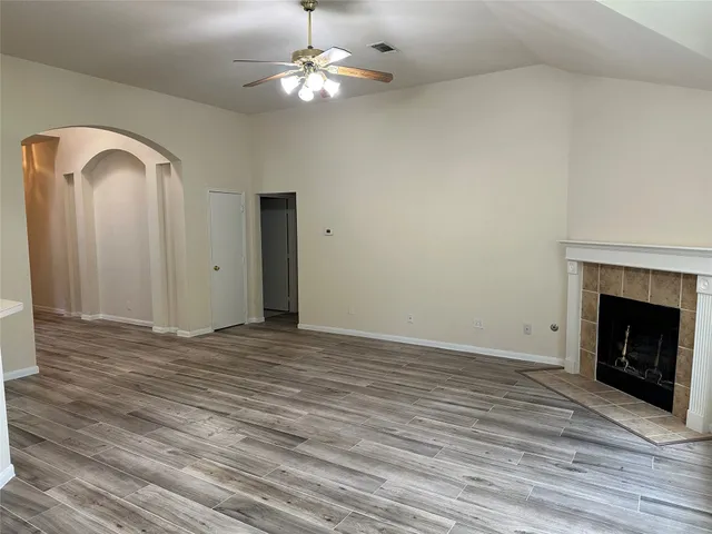an empty room with a chandelier fan and windows