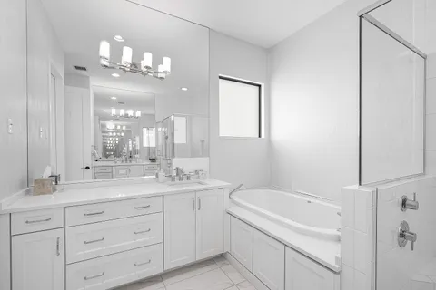 a spacious bathroom with a granite countertop sink a mirror a bathtub and shower