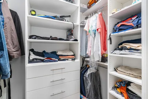a view of walk in closet with clothes and shoes