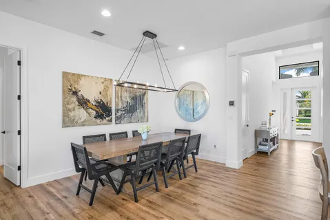 a dining room with wooden floor a glass table and chairs