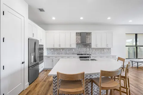 a kitchen with a dining table chairs refrigerator and cabinets