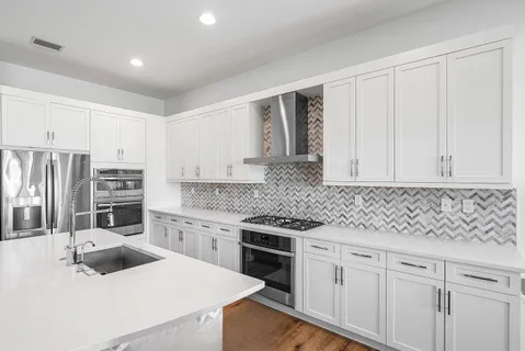 a kitchen with granite countertop a sink stainless steel appliances and cabinets