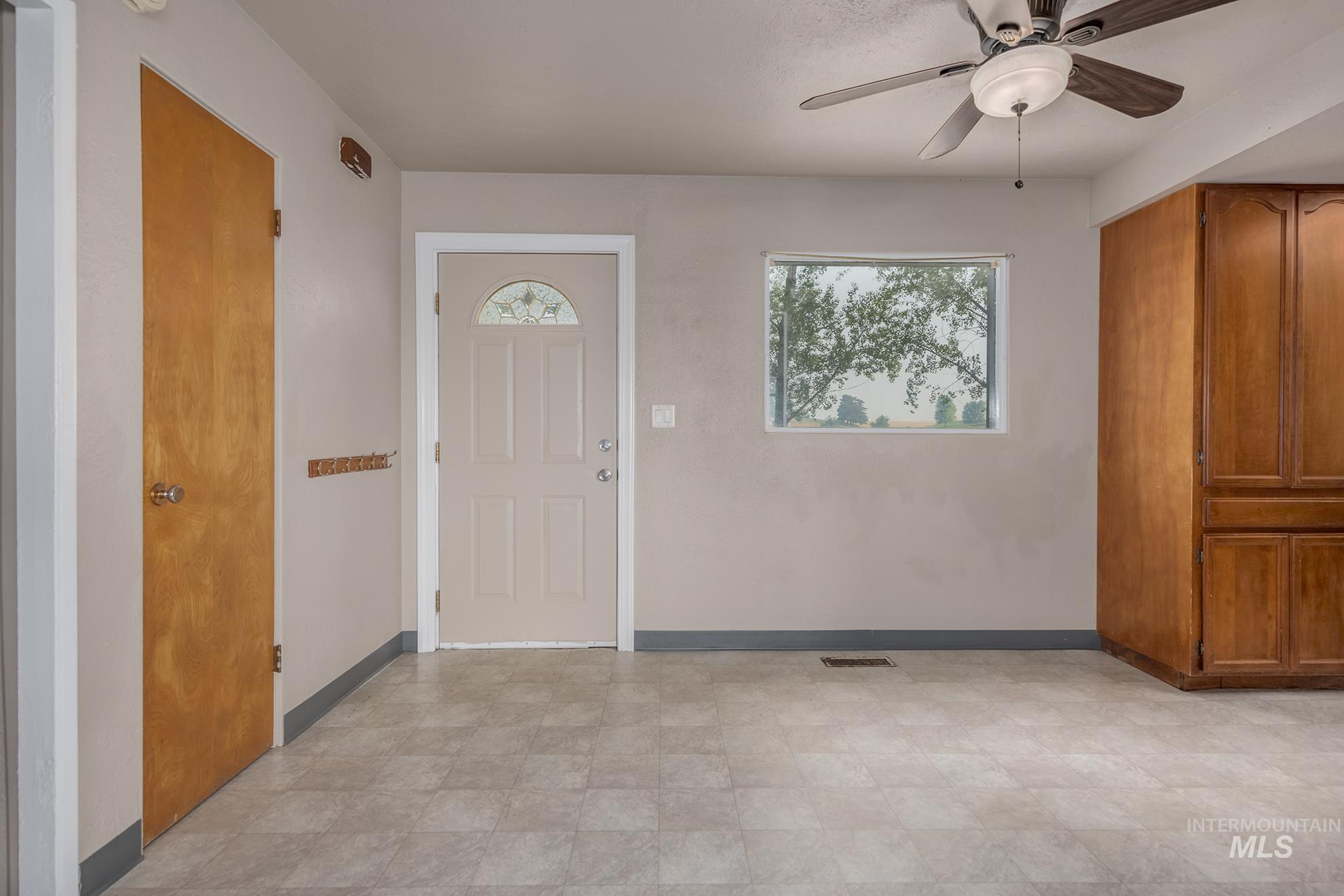 1741 Cove Road Weiser, ID 83672 - Photo 11 of 46 Entry area featuring a neutral-toned main door with decorative glass, tile flooring, a window offering exterior views, and a ceiling fan