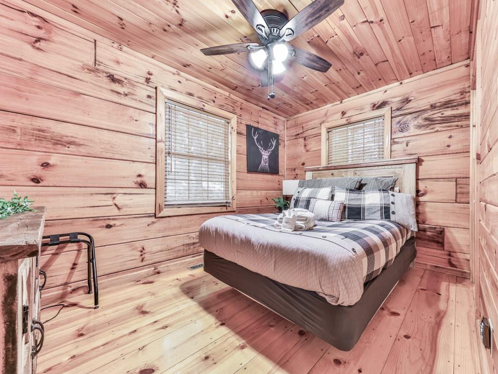 189 Smith Hill Road Blue Ridge, GA 30513 - Photo 17 of 29 a spacious bedroom with a bed a dresser and a chandelier