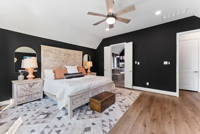 a bedroom with a bed a computer on the desk and a book shelf