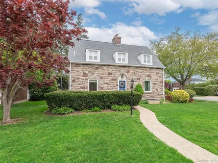 a view of a brick house with a big yard and large trees