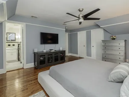 a spacious bedroom with a bed and a flat screen tv