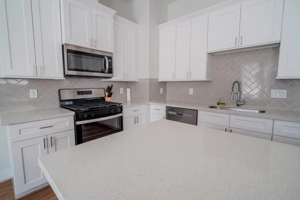 a kitchen with granite countertop white cabinets and stainless steel appliances