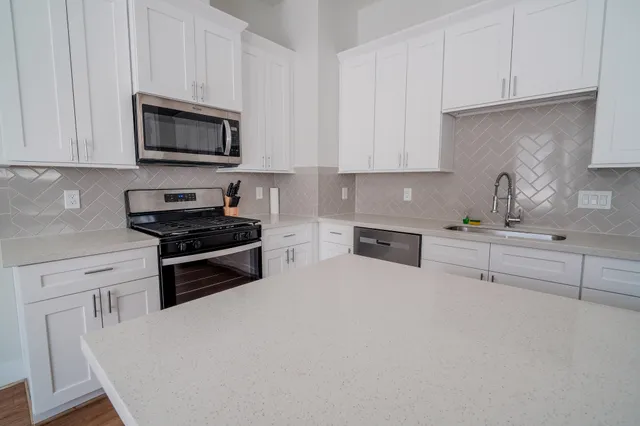 a kitchen with granite countertop white cabinets and stainless steel appliances