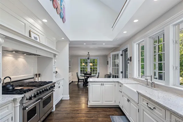 a large white kitchen with stainless steel appliances granite countertop a stove and a sink