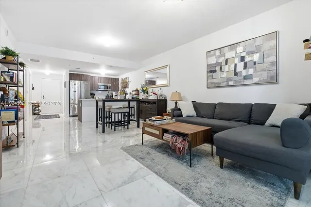 a living room with furniture and a dining table with bookshelf
