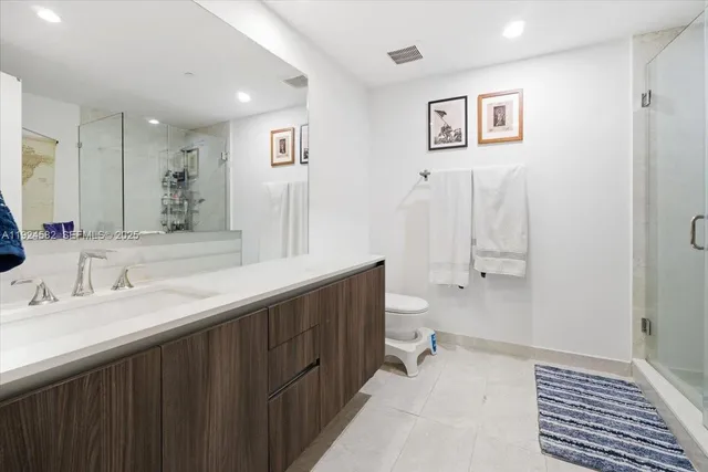 a spacious bathroom with a double vanity sink a mirror and a toilet