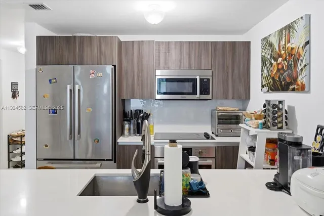 a kitchen with stainless steel appliances a stove a sink a microwave and wooden cabinets