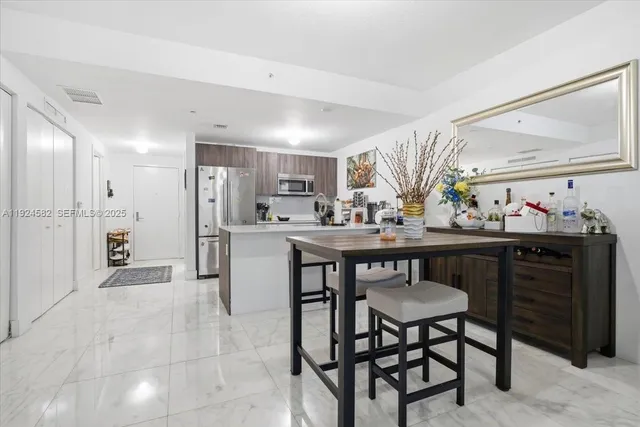 a kitchen with stainless steel appliances kitchen island granite countertop a table chairs sink and cabinets