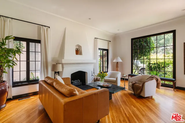 a living room with furniture fireplace and large windows