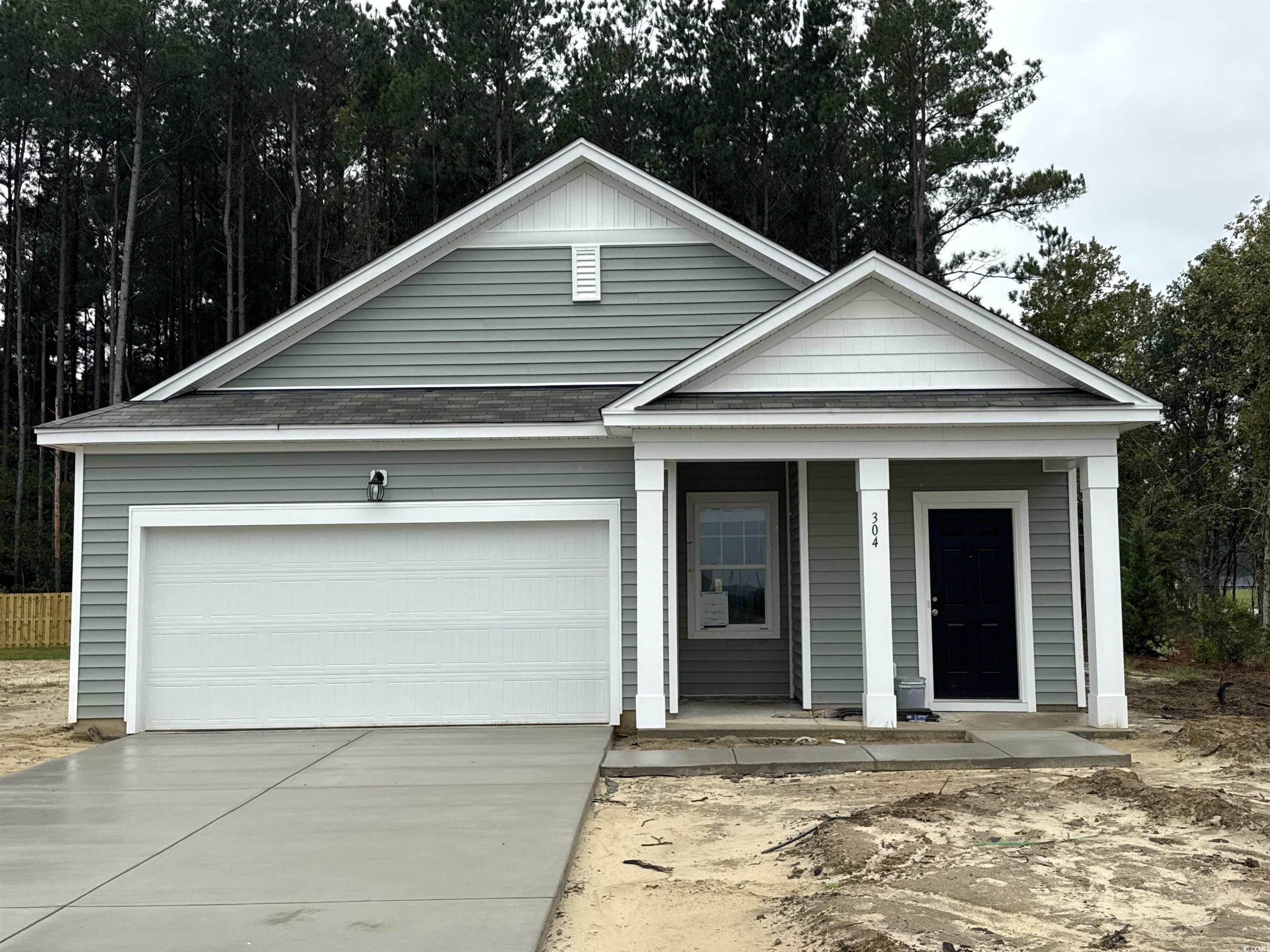 View of front of property featuring covered porch, driveway, and a garage