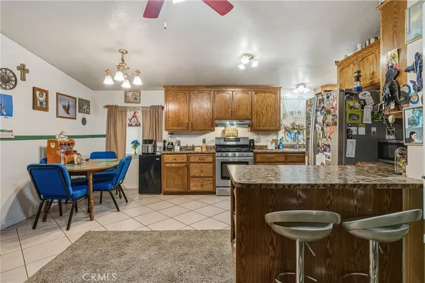 a kitchen with stainless steel appliances kitchen island granite countertop a table chairs sink and cabinets