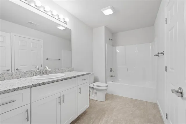 a bathroom with a granite countertop sink a toilet and bathtub
