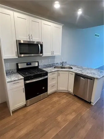 a kitchen with stainless steel appliances granite countertop a stove a sink and a microwave