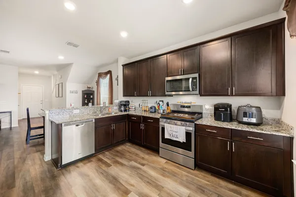 a kitchen with stainless steel appliances granite countertop wooden cabinets a stove top oven a sink and dishwasher