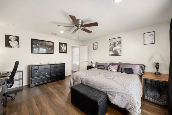 a bedroom with a bed dresser and wooden floor