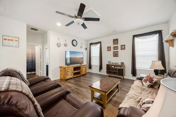 a living room with furniture ceiling fan and a flat screen tv