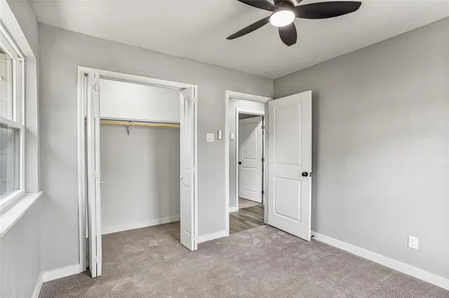 a view of an empty room and chandelier fan