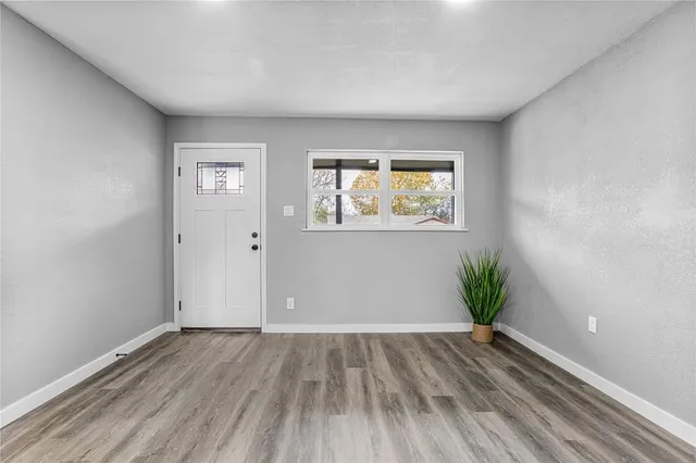 an empty room with wooden floor and windows