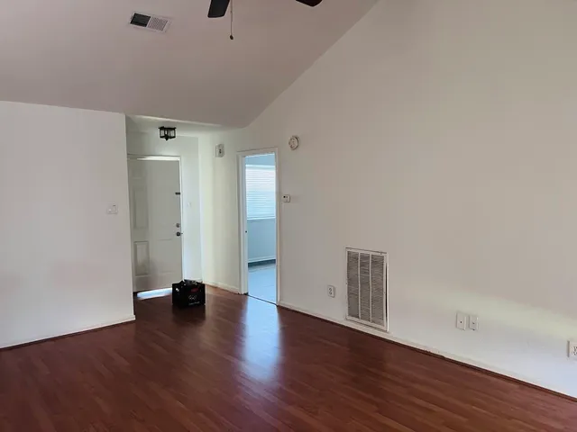 an empty room with wooden floor fireplace and windows