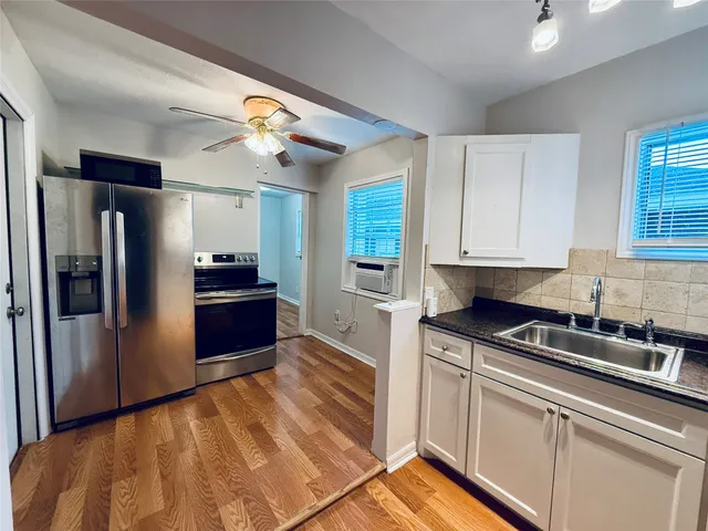 a kitchen with stainless steel appliances granite countertop a refrigerator a sink and white cabinets