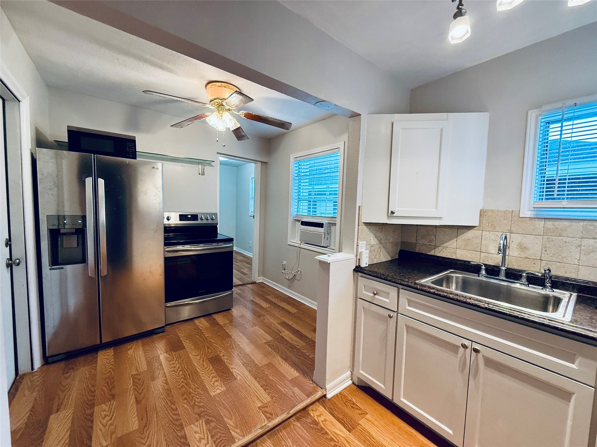 a kitchen with stainless steel appliances granite countertop a refrigerator a sink and white cabinets