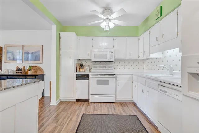 a kitchen with granite countertop white cabinets and white appliances