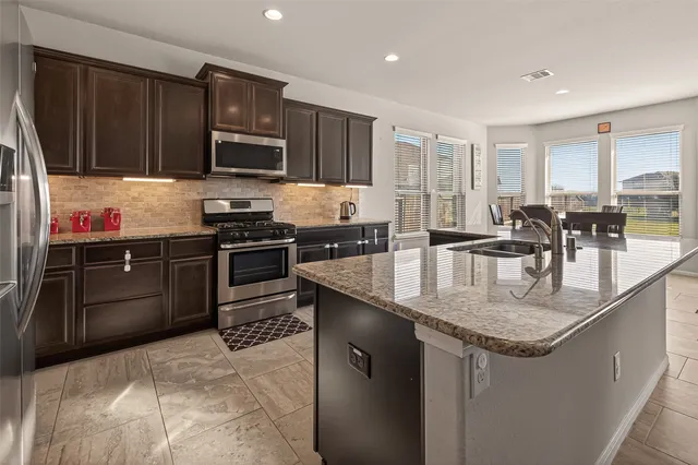 a kitchen with stainless steel appliances granite countertop a sink stove and refrigerator