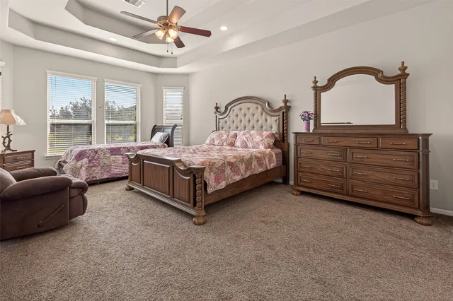 a spacious bedroom with a bed a chandelier and a dresser
