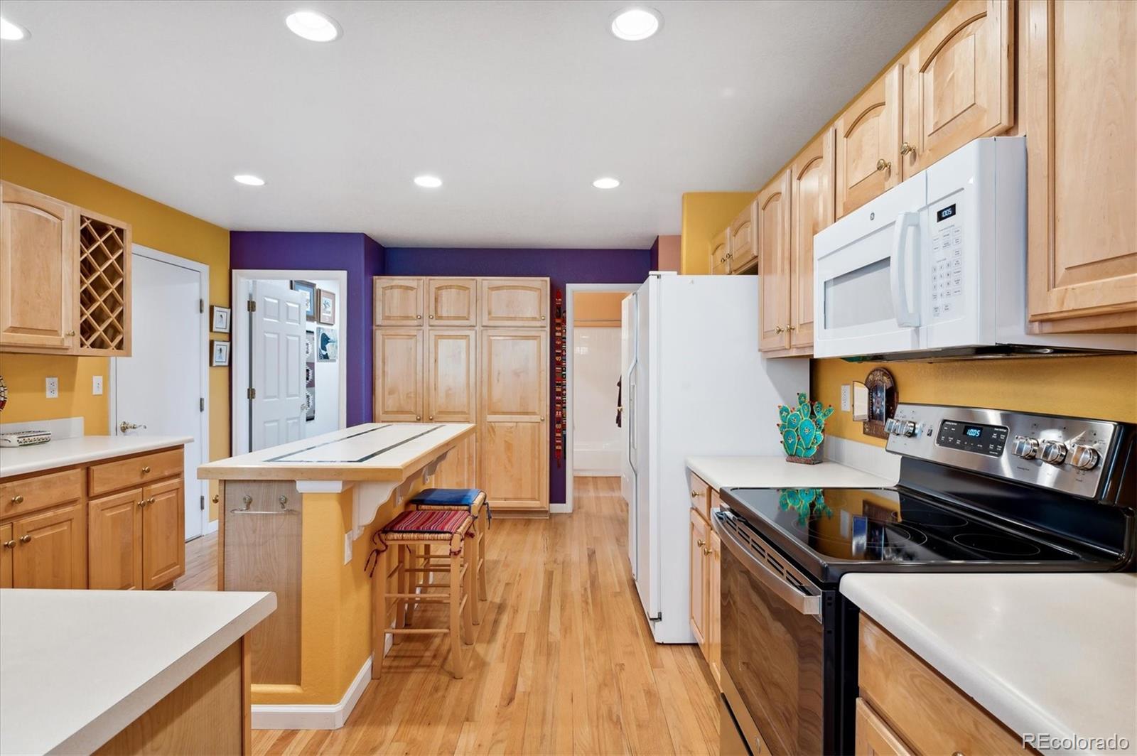 6381 Deframe Way Arvada, CO 80004 - Photo 4 of 22 a kitchen with stainless steel appliances a stove a refrigerator a sink dishwasher and a dining table with wooden floor