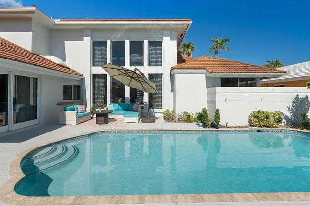 a view of a patio with couches table and chairs under an umbrella with a barbeque