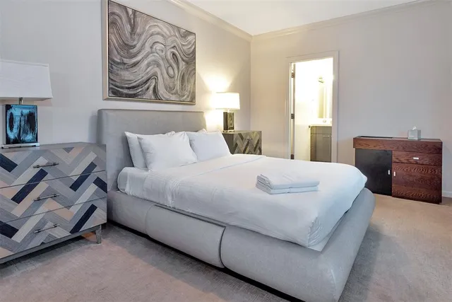 a bedroom with a large bed and flat tv screen on dresser