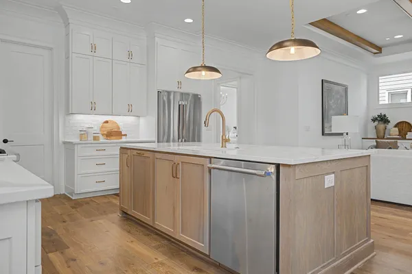 a kitchen with stainless steel appliances kitchen island a table chairs in it and white cabinets